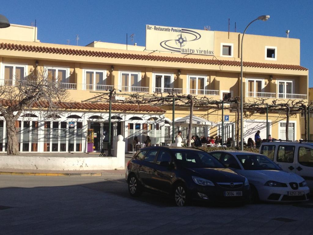 two cars parked in a parking lot in front of a building at Pension Cuatro Vientos in Cuevas del Almanzora