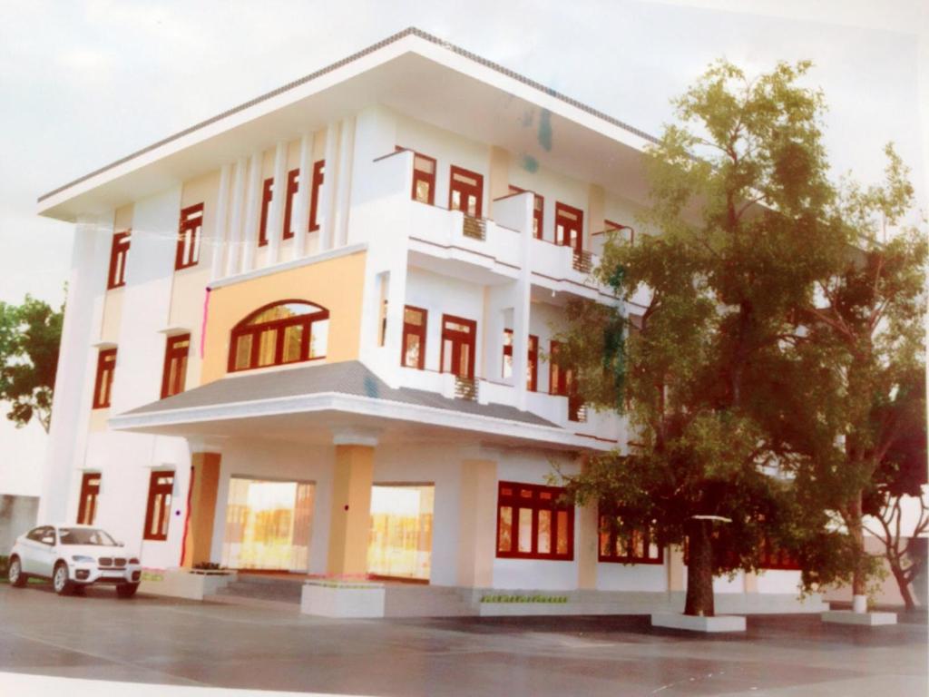 un edificio blanco con un coche aparcado delante de él en Nhà Khách T284, en Buon Ma Thuot