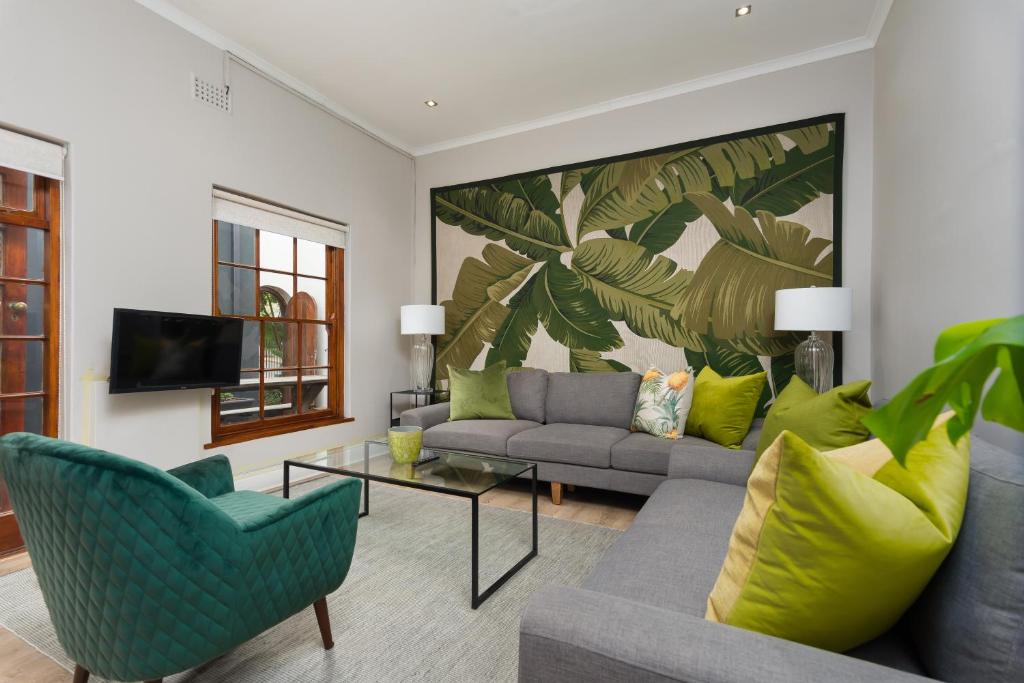 a living room with a couch and chairs and a tv at Vesperdene Mews 2 in Cape Town