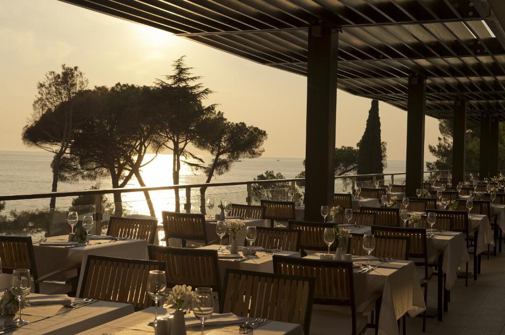 a restaurant with tables and chairs with a view of the ocean at Hotel Parentium Plava Laguna in Poreč