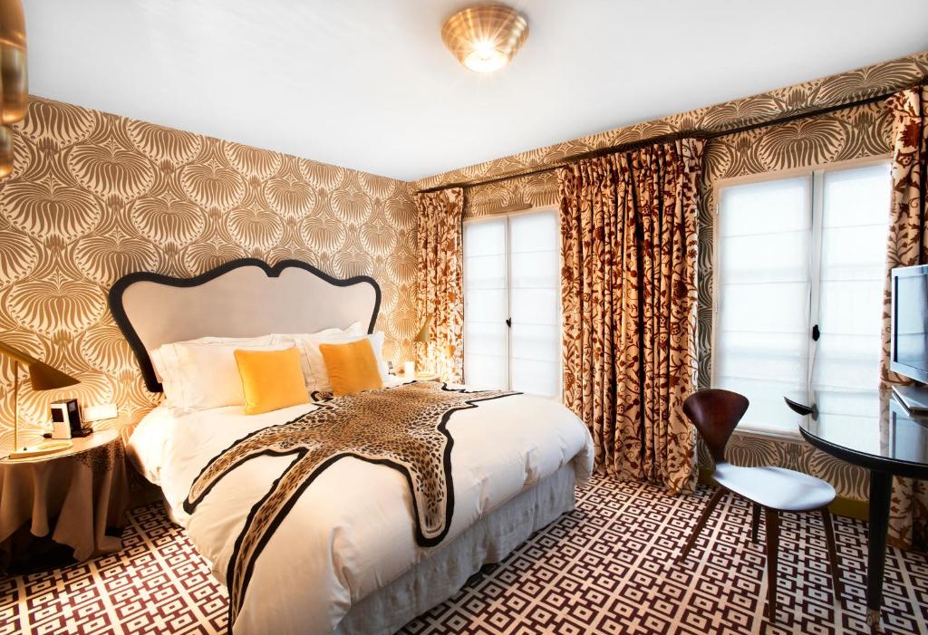 a bedroom with a large bed and a desk at Hôtel Thoumieux in Paris