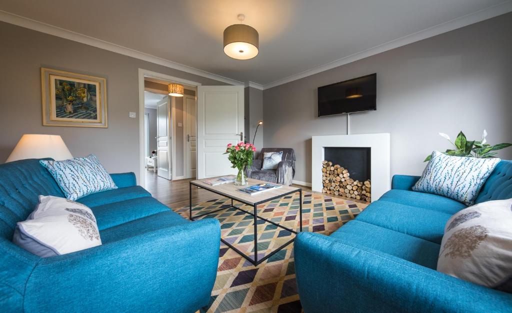 a living room with blue couches and a fireplace at Taigh Mhuirne in Portree