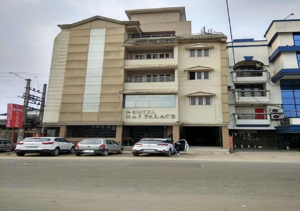 a large building with cars parked in front of it at Hotel Raj Palace in Dibrugarh