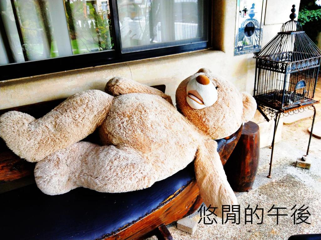 a large teddy bear sitting on a bench next to a window at Borabora B&amp;B in Nanwan