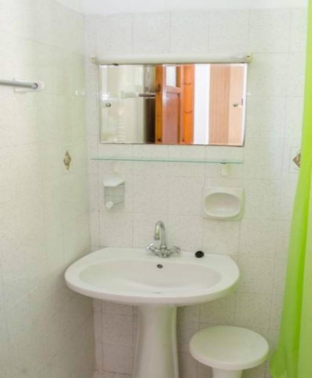 a white bathroom with a sink and a mirror at Kristi in Póros Kefalonias