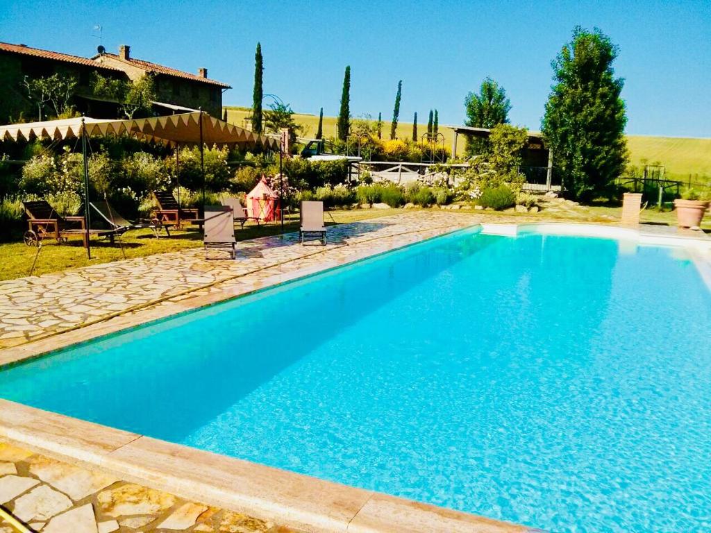 ein großer blauer Pool mit Stühlen und ein Haus in der Unterkunft Fontegirasole - a Fontanaro Property in Paciano