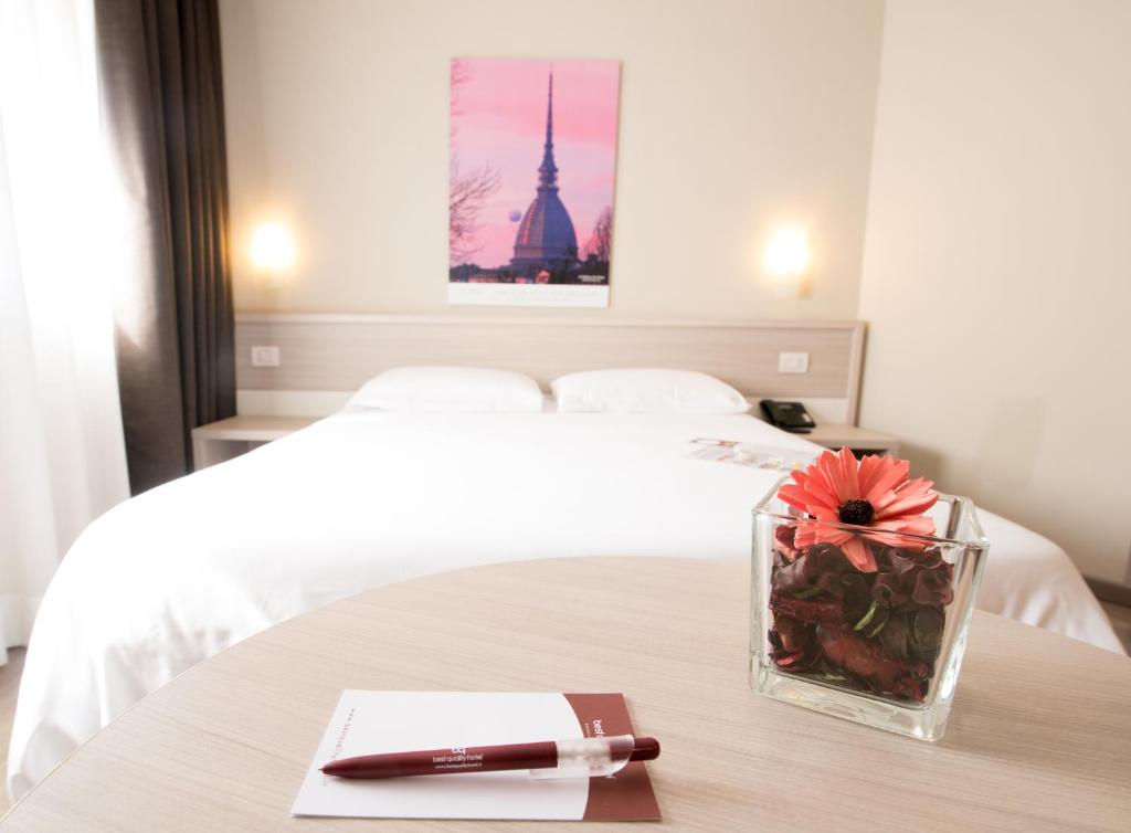 um quarto com uma cama e uma mesa com uma caneta em Best Quality Hotel Politecnico em Turim