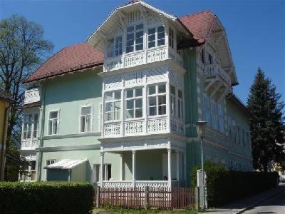 ein großes, grün-weißes Haus mit einer Veranda in der Unterkunft Raisa Apartments Fünkhgasse in Pressbaum