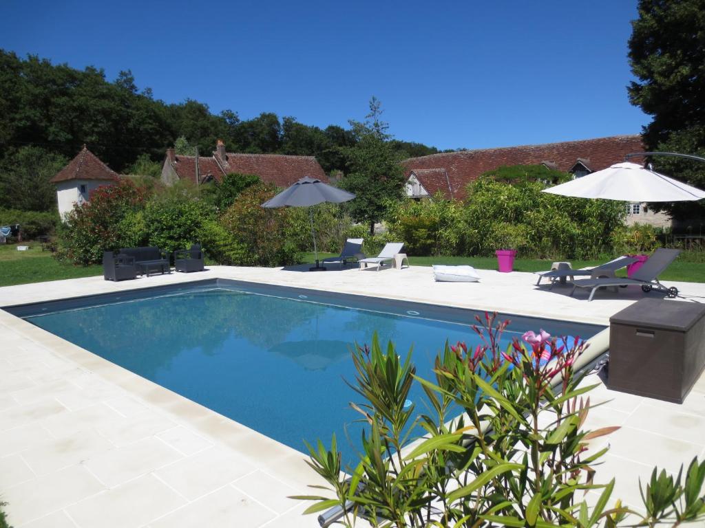 una piscina con sillas y sombrillas en un patio en Le Grand Coudreau, en Nazelles