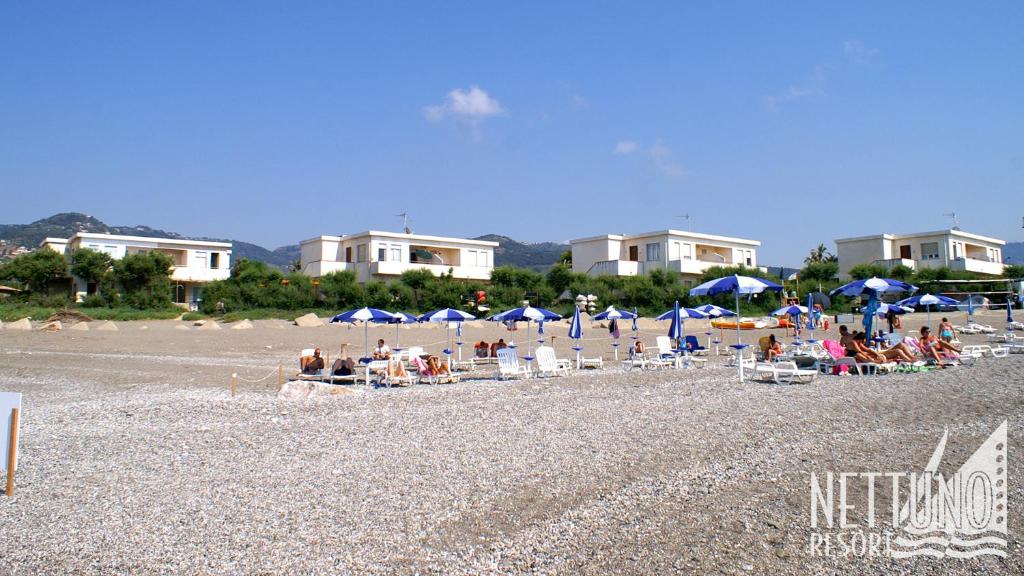 un grupo de personas sentadas en una playa con sombrillas en Nettuno Resort en Capo dʼOrlando