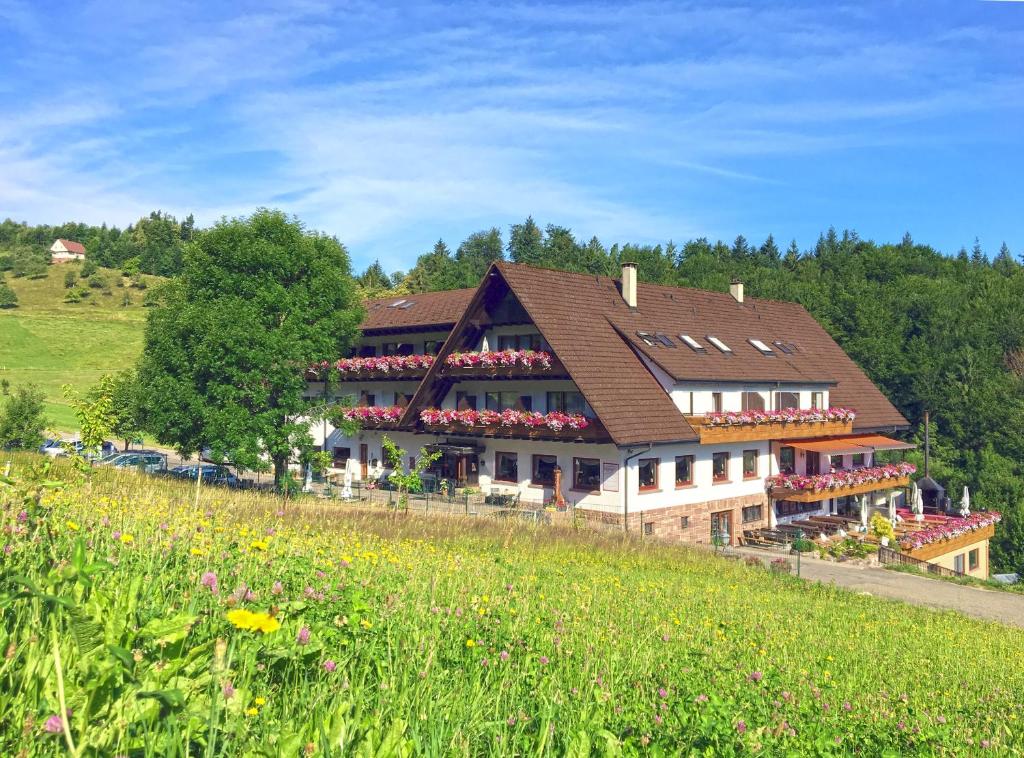 um grande edifício com flores em frente a um campo em Höhenhotel & Restaurant Kalikutt em Oppenau