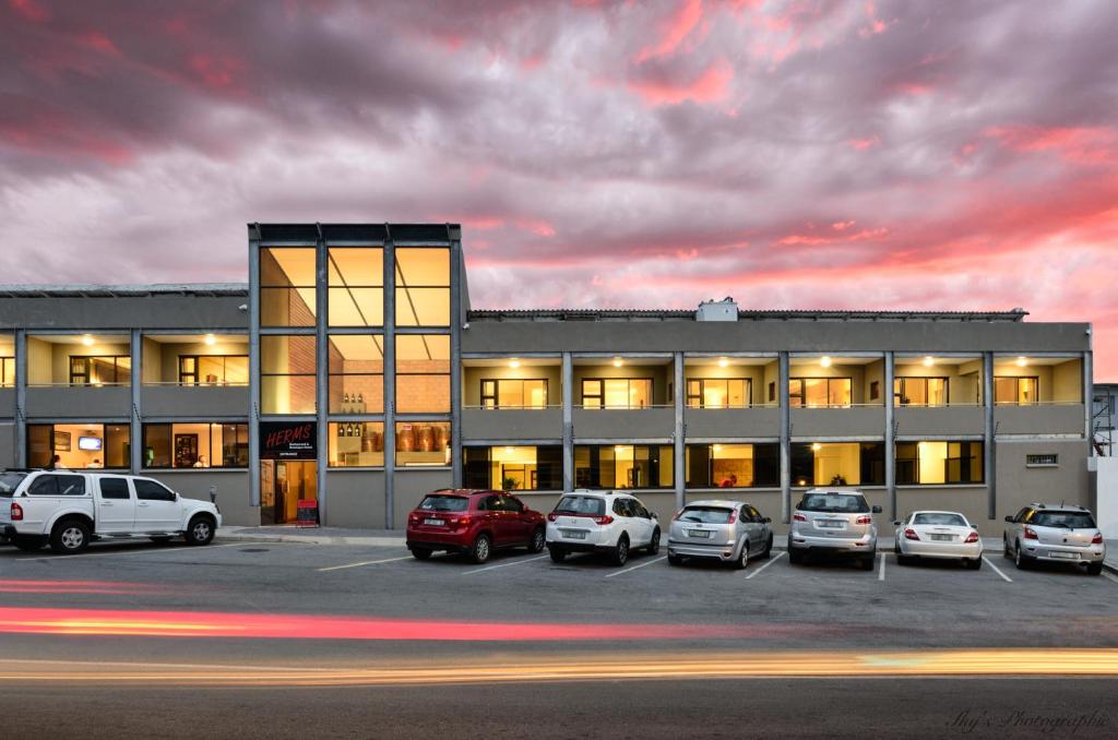un edificio con coches estacionados en un estacionamiento en HERMS Restaurant & Boutique Hotel, en Port Elizabeth