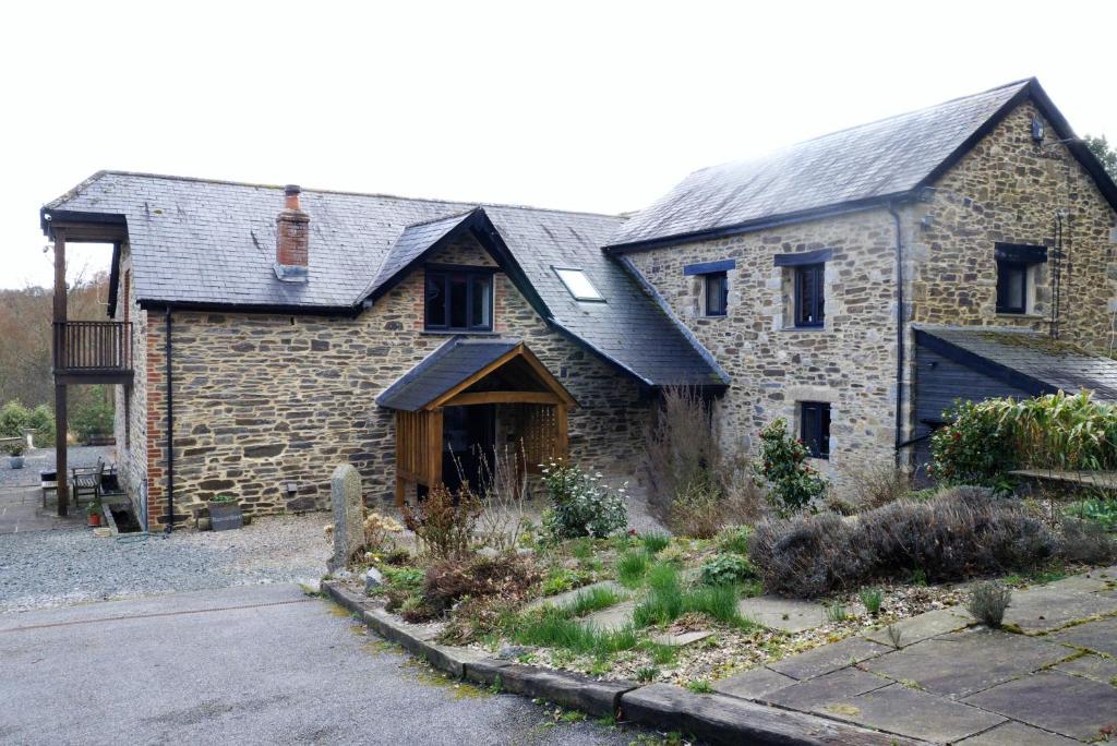 an old stone house with a black roof at The Buttery at Trussel Barn in Liskeard