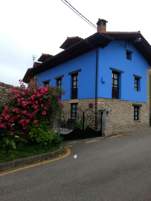 a blue house with a flowering bush at La Ería de Colombres in Colombres
