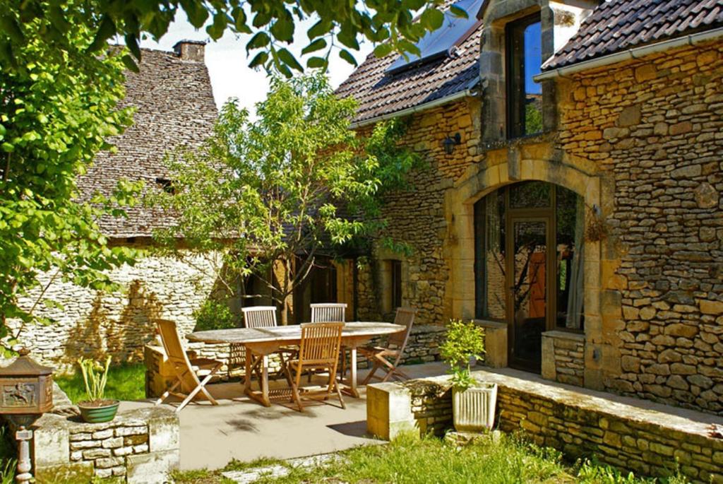 une terrasse avec une table et des chaises devant un bâtiment dans l'établissement La Ferme du Pech, à Saint-Geniès