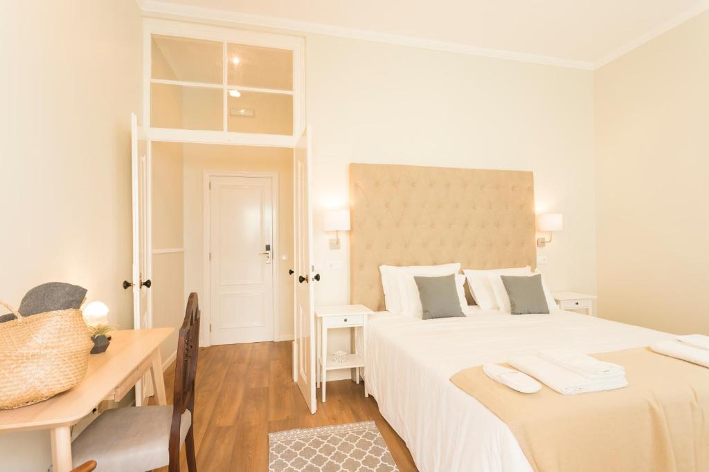 a white bedroom with two beds and a desk at Ericeira Soul Guesthouse in Ericeira