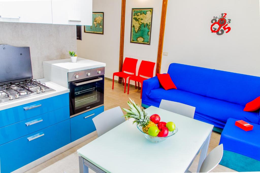 eine Küche mit einem blauen Sofa und einem Tisch mit einer Schale Obst in der Unterkunft Domus Cephaledium in Cefalú