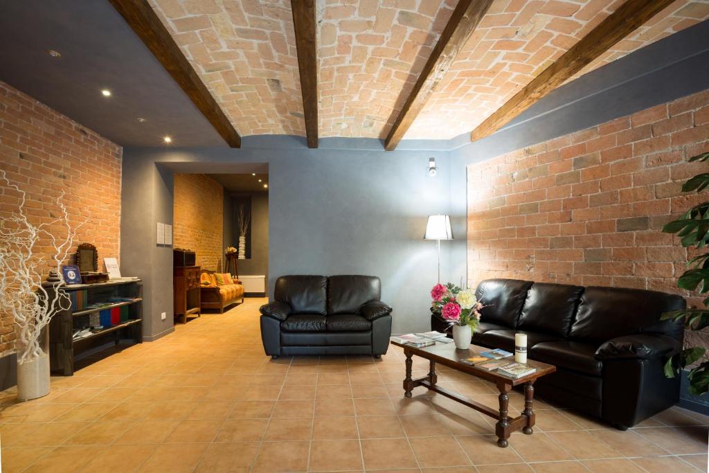 un soggiorno con mobili in pelle nera e un muro di mattoni di Camere Centro Storico a Canelli