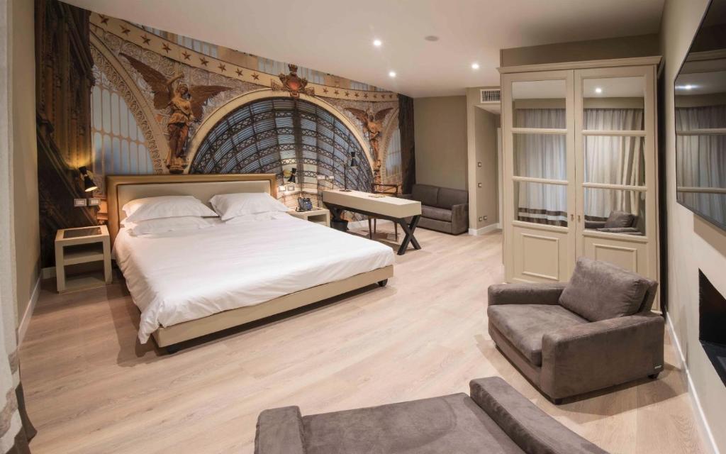 um quarto com uma cama, uma cadeira e uma secretária em Caruso Place Boutique & Wellness Suites em Nápoles