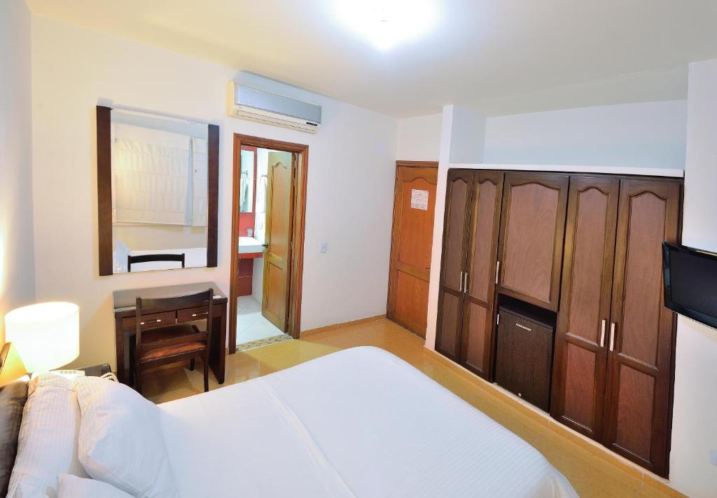 a bedroom with a bed and a desk and a mirror at Hotel Palonegro in Bucaramanga