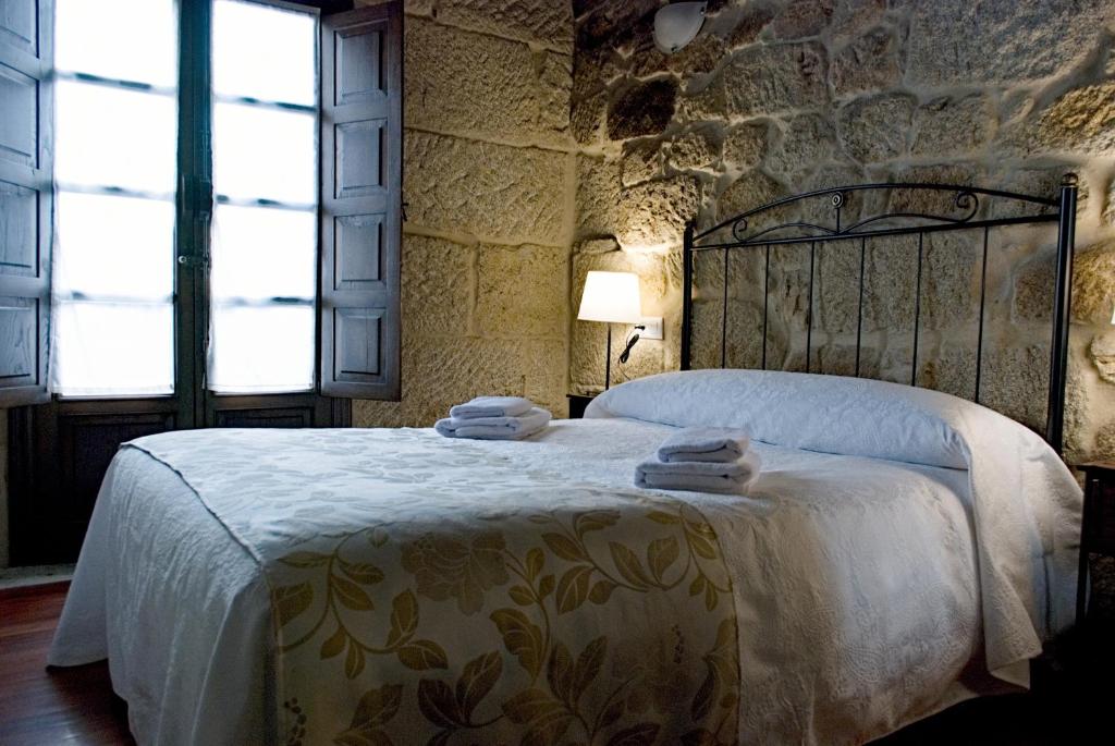 een slaapkamer met een groot bed in een stenen muur bij A Lareira De Allariz in Allariz