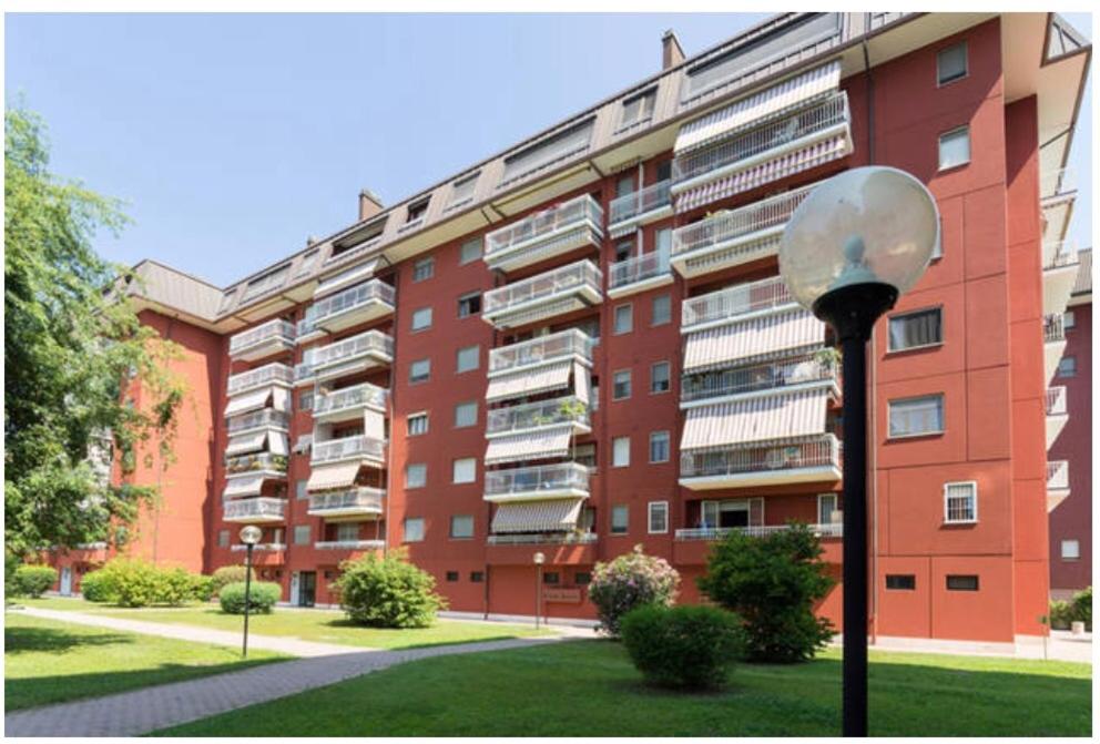 duży czerwony budynek apartamentowy z światłem ulicznym przed nim w obiekcie Apartment Forum 2 w mieście Assago