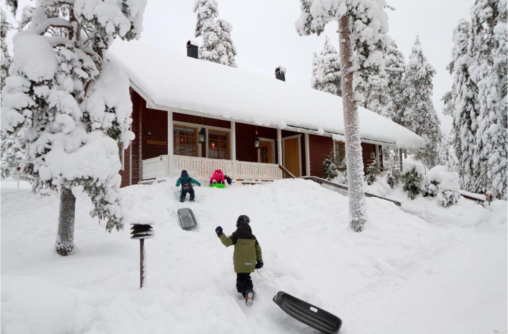 a person standing in the snow in front of a house at Villa Kyyhkynen in Rovaniemi