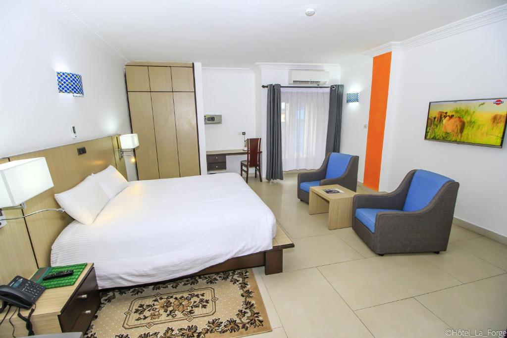 a hotel room with a bed and two chairs at Hotel LAFORGE in Abidjan