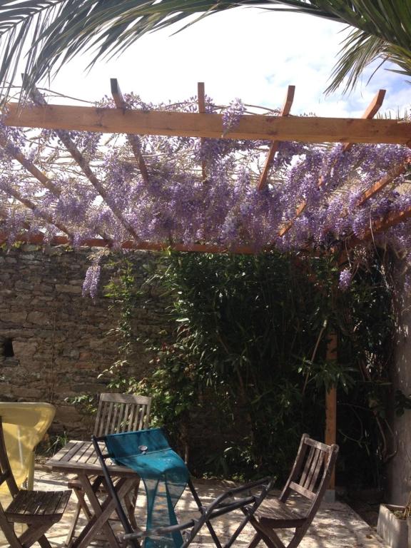 a patio with chairs and a pergola with purple flowers at Olive et Pomme in Bretteville