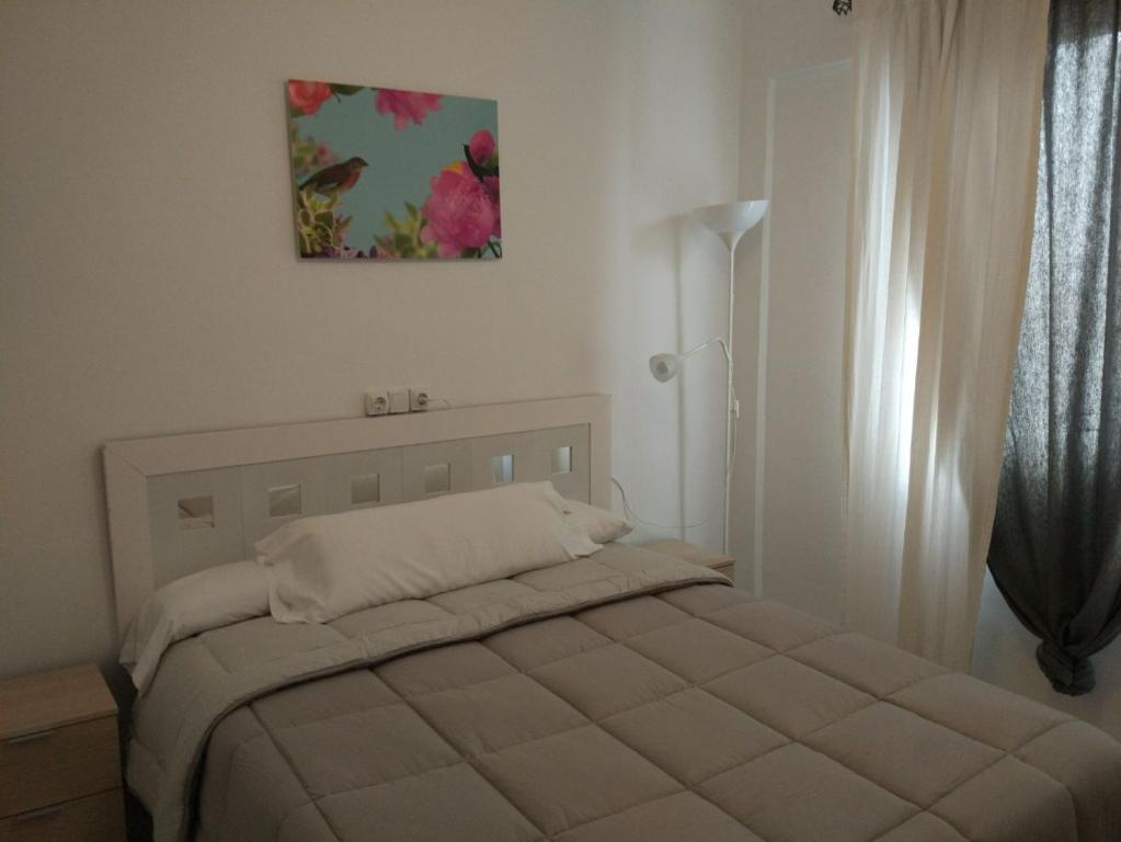 アンテケラにあるApartamento Alameda de Andalucía de Antequeraのベッドルーム1室(ベッド1台付)が備わります。壁には絵画が飾られています。