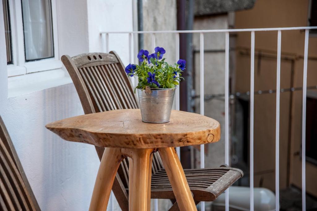 - une petite table en bois avec un seau de fleurs dans l'établissement B&B Al Vicolo del Gallo, à Varallo