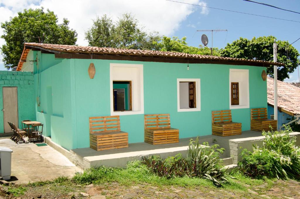 a blue house with chairs in front of it at Ilha Hostel in Fernando de Noronha