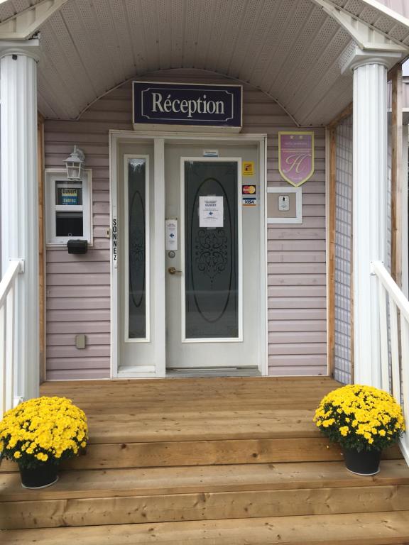 une maison avec une porte et une véranda ornée de fleurs jaunes dans l'établissement Auberge Motel Panorama, à Lac-Bouchette