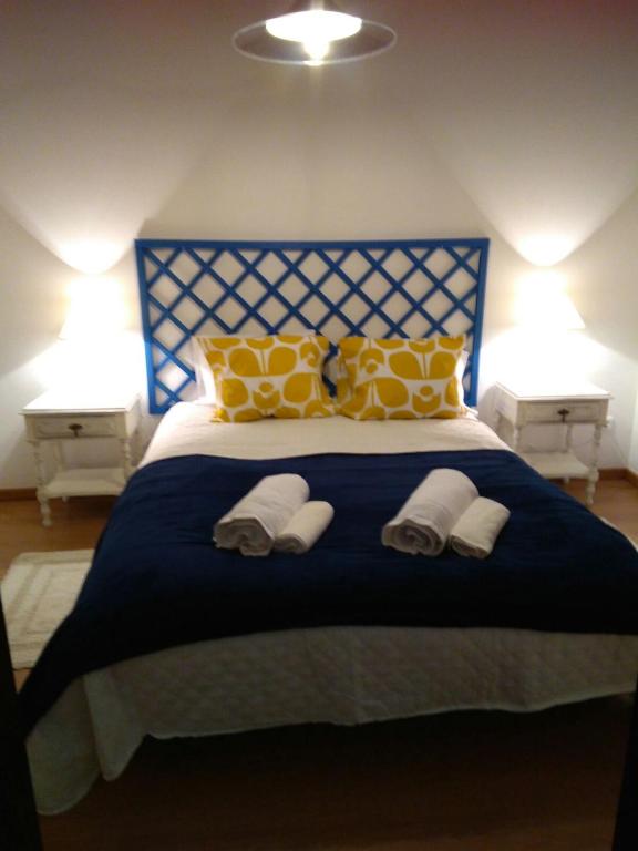 a bedroom with a blue bed with yellow and white pillows at Estevas de Monsaraz in Monsaraz