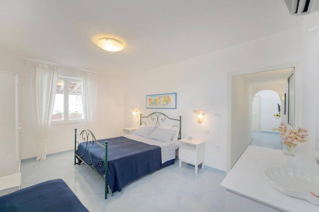 a white bedroom with a bed and a bathroom at Le Querce in Procida