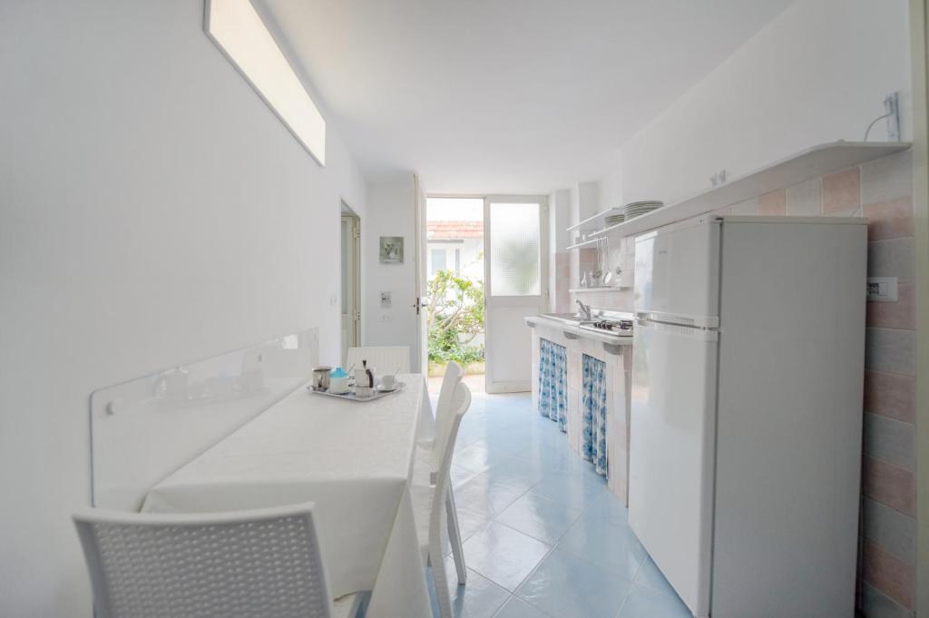 a white kitchen with a white table and chairs at Le Querce in Procida