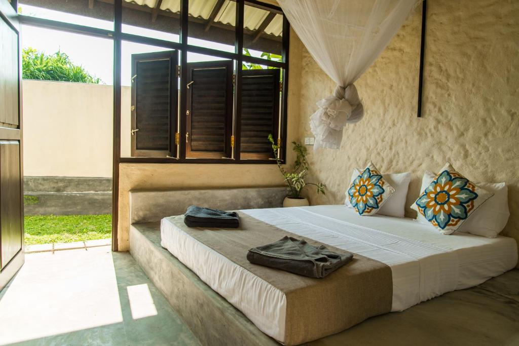 a bedroom with a bed and a large window at Lime & Co Midi in Weligama
