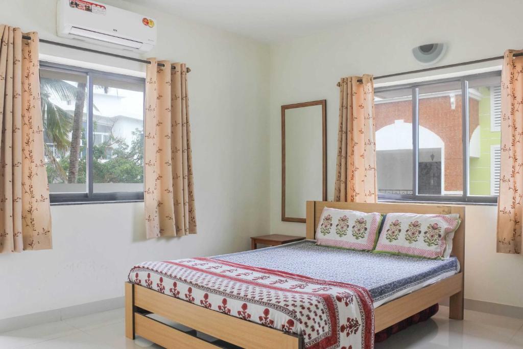 a bedroom with a bed and two windows at Sun & Sand in Candolim