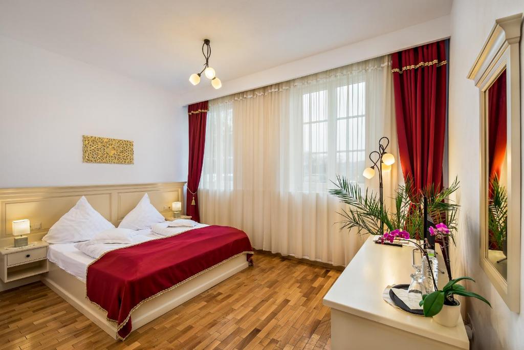 um quarto de hotel com uma cama com um cobertor vermelho em Palatul Brukenthal Avrig em Avrig