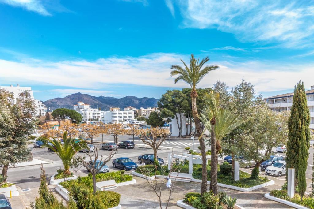 a parking lot with palm trees and buildings at Holidays Royal Marine in Roses