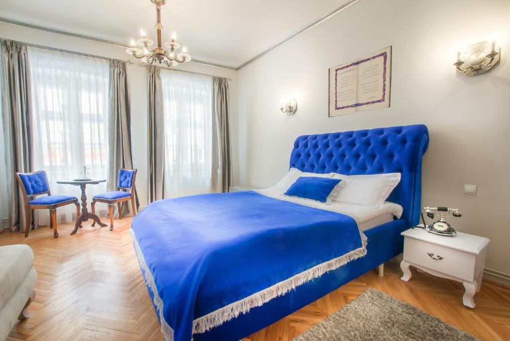 1 cama azul en un dormitorio con mesa y sillas en Casa Antiqua, en Brasov