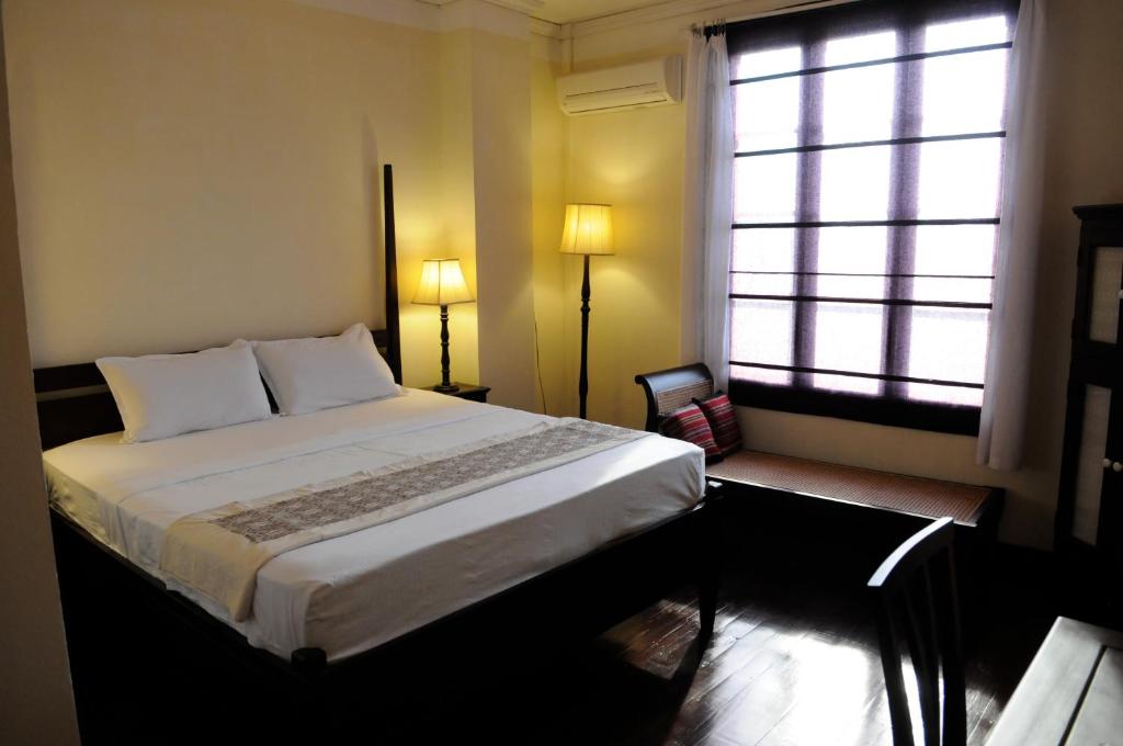 a bedroom with a large bed and a window at Hotel Khamvongsa in Vientiane