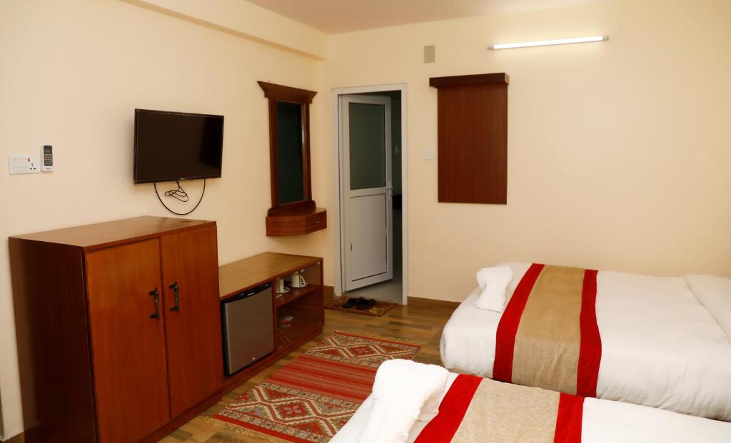 una camera con letto, TV e copriletto di Hotel Guru a Pokhara