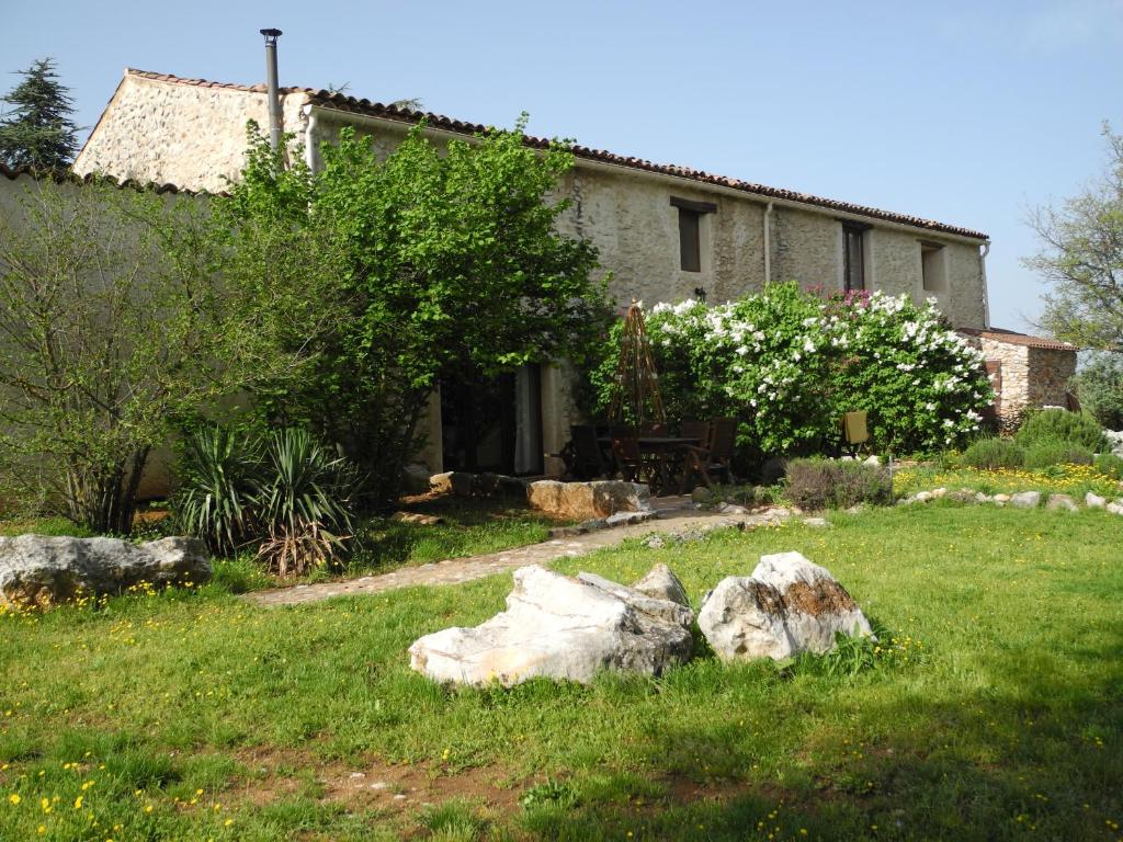 a house with a garden with a rock in the yard at Le Mas De La Chérine in Quinson
