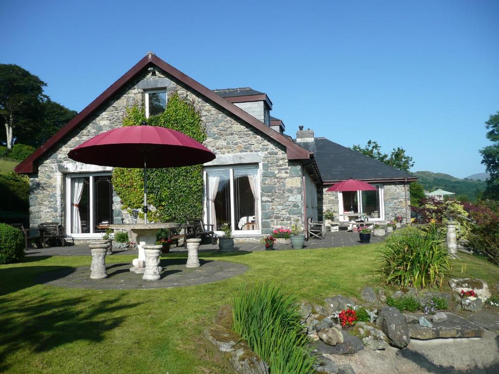 a house with a table with an umbrella in the yard at Heulwen Guest House in Dolgellau