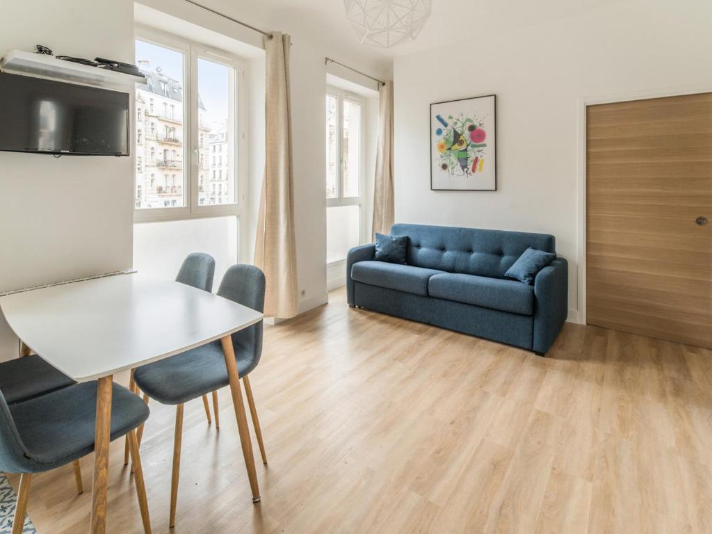 パリにあるWelkeys - Bonne Nouvelle Apartmentのリビングルーム(青いソファ、テーブル付)