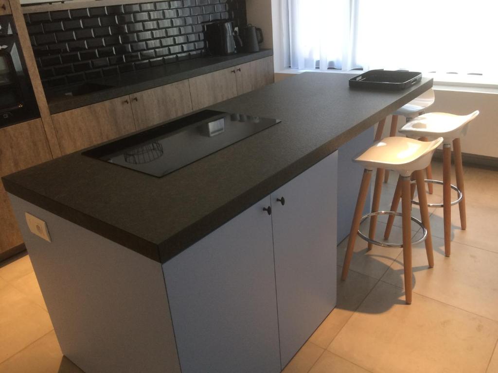 a kitchen with a black counter top and stools at ChilloutOostende in Ostend
