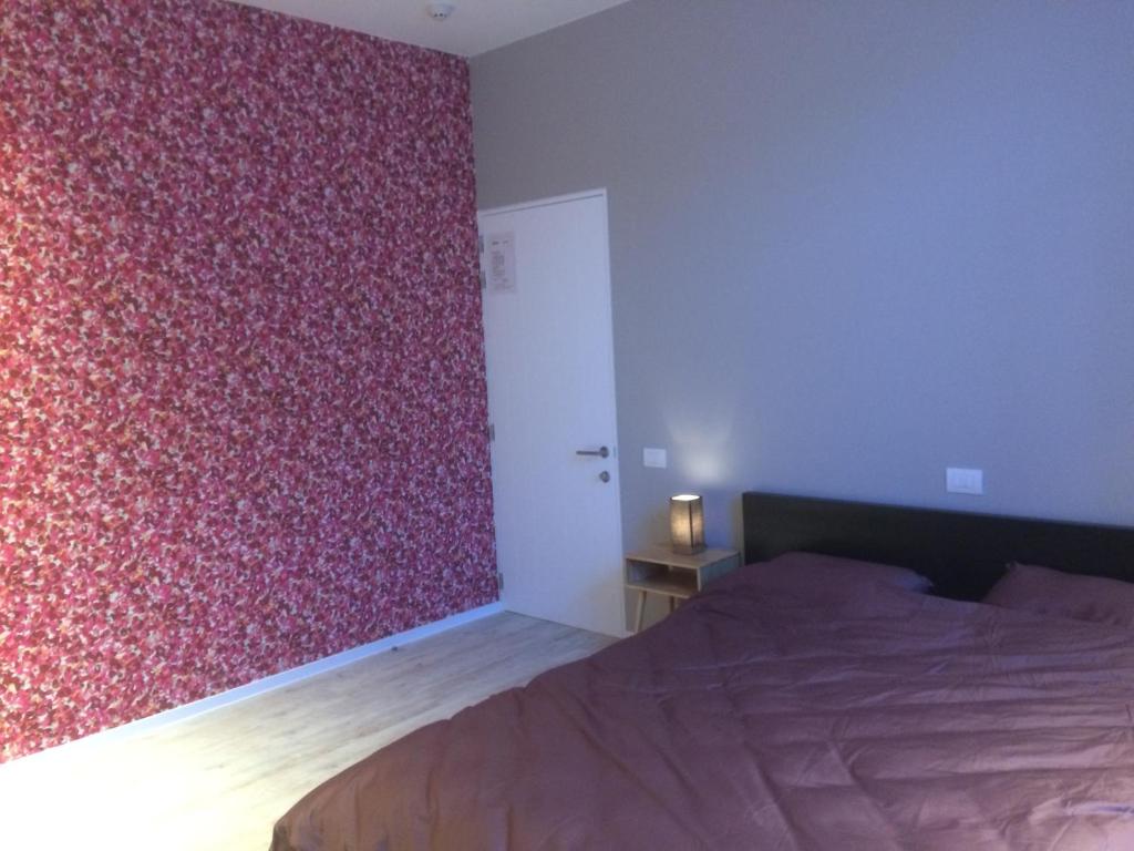 a bedroom with a bed and a red wall at ChilloutOostende in Ostend
