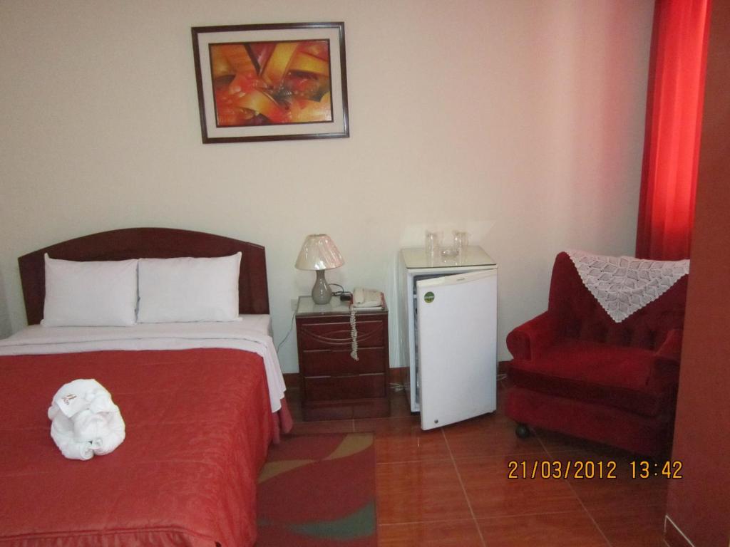 a bedroom with a bed and a red chair at Hotel Plaza Trujillo in Trujillo