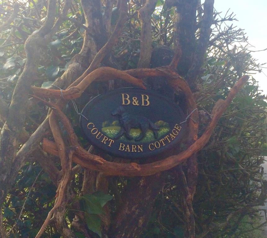 una señal para una comisión de bar en un árbol en Court Barn Cottage B&B en Burwash